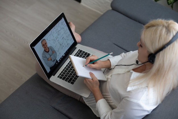 Foto hermosa mujer revisando su lección con su computadora portátil y libro