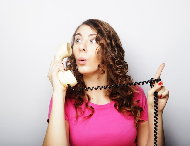 Hermosa mujer rizada sorprendida hablando por teléfono vintage blanco aislado sobre fondo blanco.