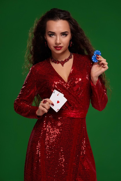 Hermosa mujer rizada en un vestido brillante sosteniendo algunas cartas y fichas de juego casino