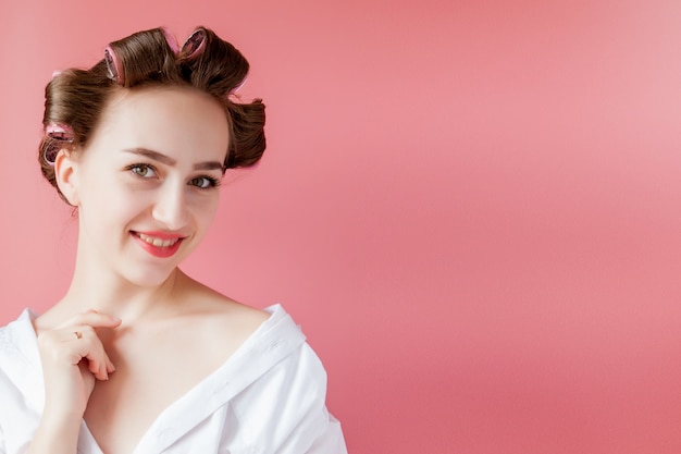 Hermosa mujer en rizadores de pelo en rosa