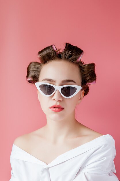 Hermosa mujer en rizadores de pelo en rosa