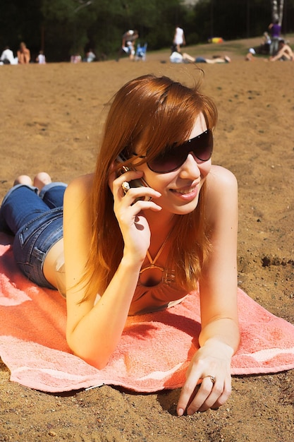 Hermosa mujer roja sexy tirada en la playa del mar