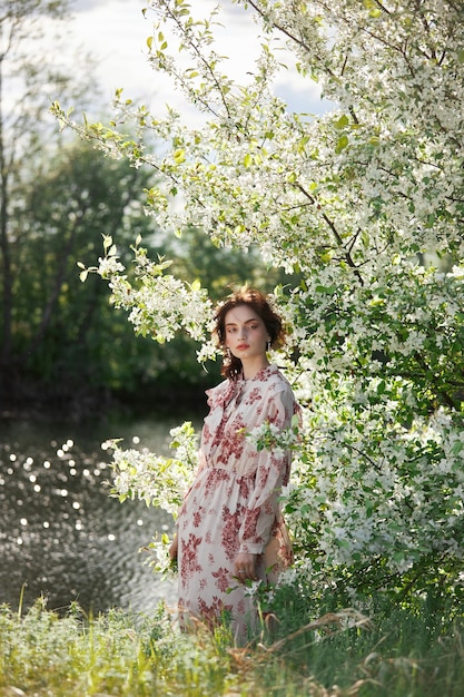 Hermosa mujer romántica se encuentra en las ramas del manzano en flor. Primavera retrato niña en flores manzano