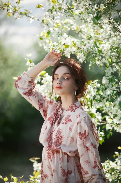 Hermosa mujer romántica se encuentra en las ramas del manzano en flor. Primavera retrato niña en flores manzano