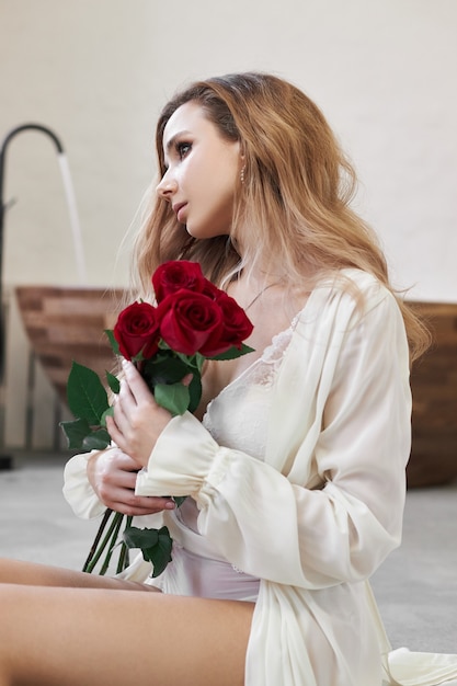 Hermosa mujer en ropa interior blanca y bata en casa en el baño