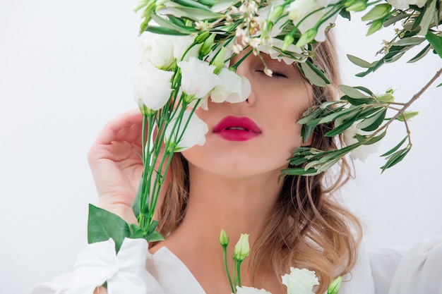 Hermosa mujer con rosas blancas en la manga, vestida con un vestido blanco. Concepto de primavera o día de San Valentín