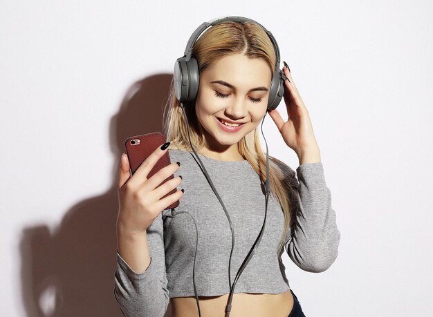 Hermosa mujer rubia en auriculares escuchando música en blanco