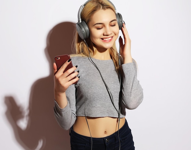 Hermosa mujer rubia en auriculares escuchando música en blanco