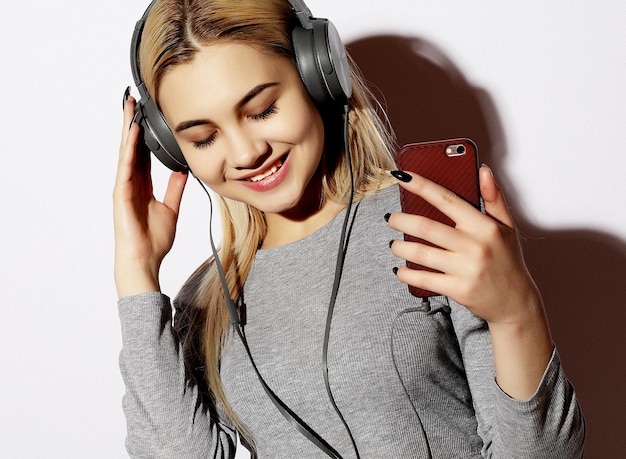 Hermosa mujer rubia en auriculares escuchando música en blanco
