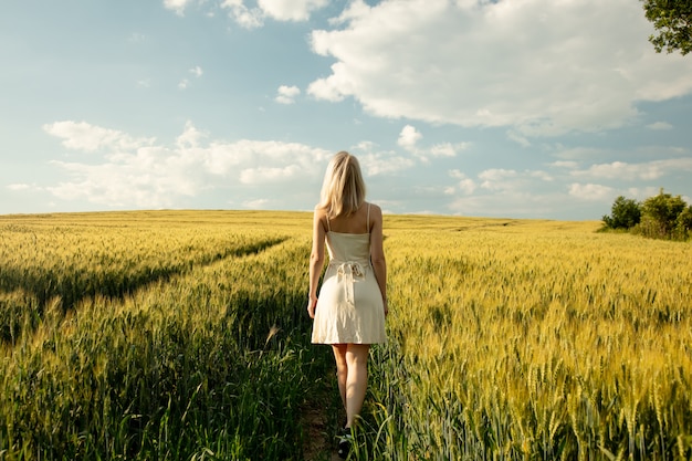 Hermosa mujer rubia en campo de trigo en la hora del atardecer