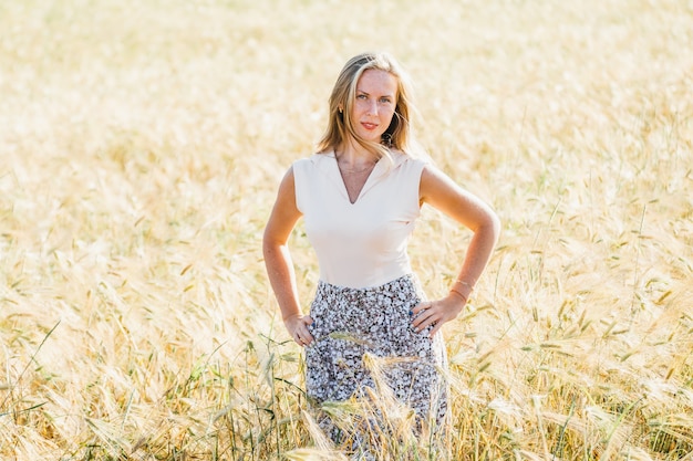 Hermosa mujer rubia en un campo de verano dorado