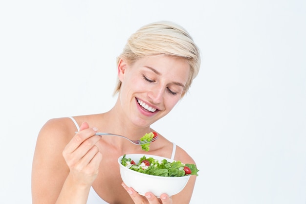 Hermosa mujer rubia comiendo ensalada