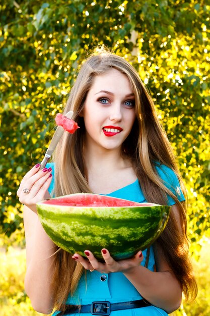 Hermosa mujer rubia comiendo una sandía al aire libre