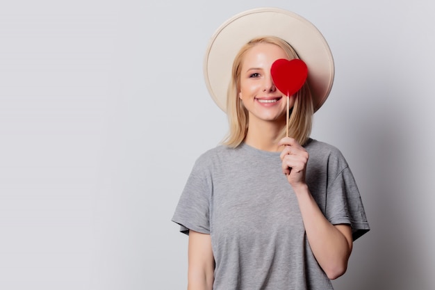 Hermosa mujer rubia con dulces en forma de corazón en la pared blanca