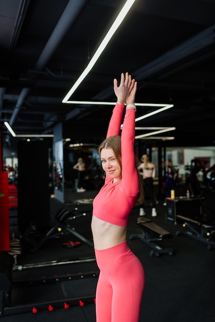 Hermosa mujer rubia en forma muscular haciendo ejercicio, construyendo músculos en el gimnasio