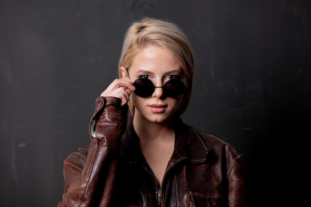 Hermosa mujer rubia en gafas de sol y chaqueta de estilo