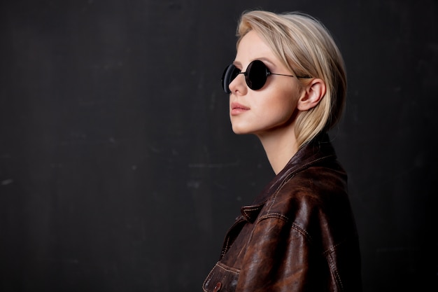 Hermosa mujer rubia en gafas de sol y chaqueta de estilo