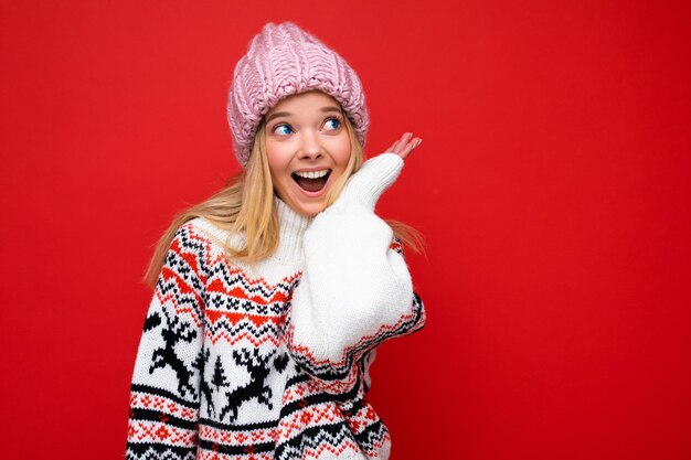 Hermosa mujer rubia joven feliz positiva aislada sobre la pared de colores de fondo vistiendo ropa casual elegante sintiendo emociones sinceras mirando hacia un lado.