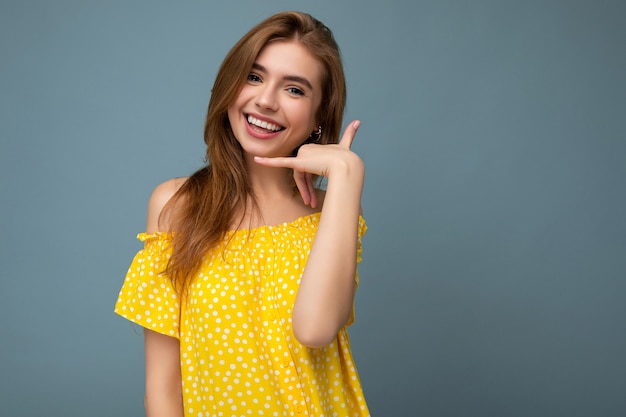 Hermosa mujer rubia joven feliz sonriente con elegante vestido amarillo de verano que se encuentran aisladas