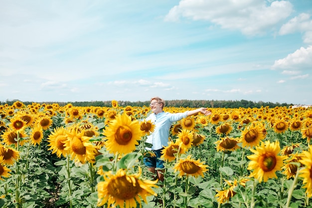 Hermosa mujer rubia joven de pie en el campo de girasol