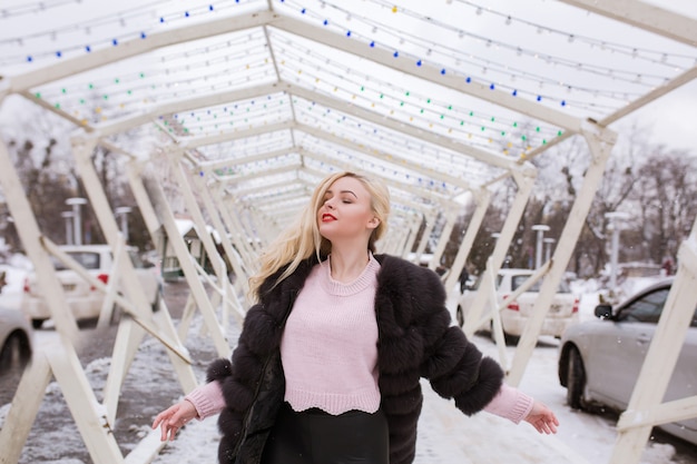 Foto hermosa mujer rubia con maquillaje brillante posando en la calle en invierno