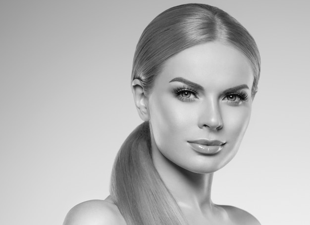 Hermosa mujer rubia con maquillaje natural de pelo largo y concepto cosmético de piel sana. Tiro del estudio. Monocromo. Gris. En blanco y negro. Tiro del estudio.