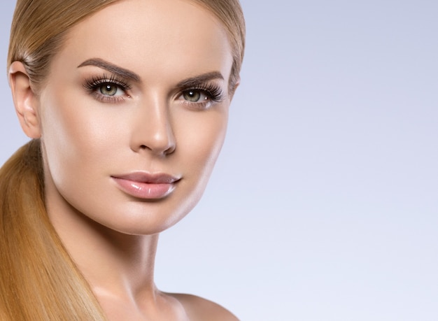 Hermosa mujer rubia con maquillaje natural de pelo largo y concepto cosmético de piel sana. Tiro del estudio.