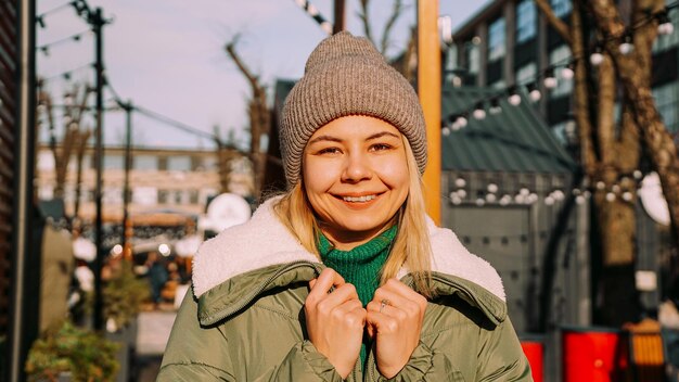 Hermosa mujer rubia mira con una sonrisa mientras está de pie al aire libre Clima perfecto para pasar el rato con amigos Espacio de arte urbano con comida callejera