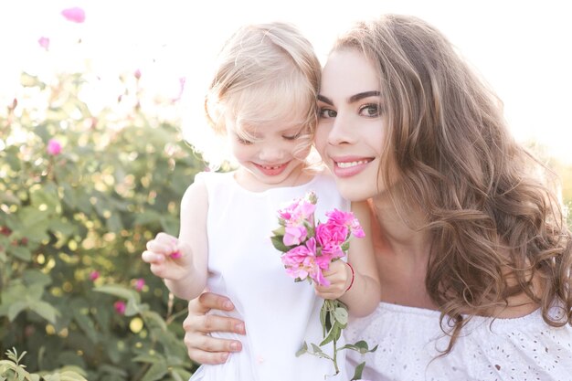 Hermosa mujer rubia con niño niña sosteniendo flores en la pradera