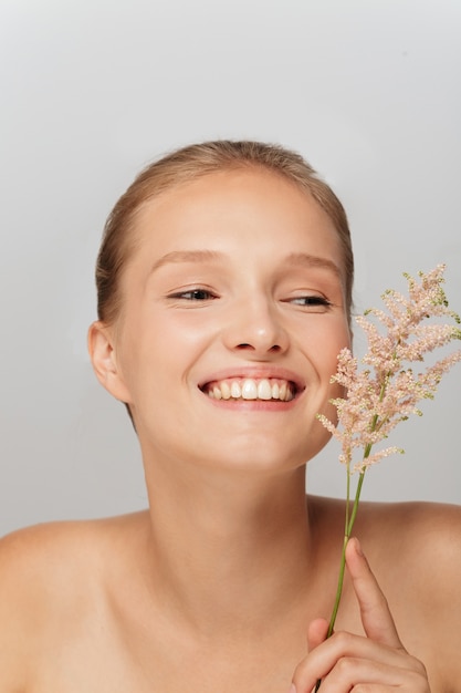 Foto hermosa mujer rubia con una piel perfecta y una rama floral