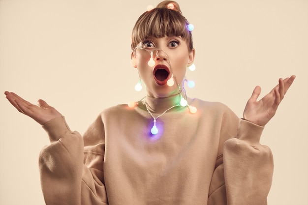 Hermosa mujer rubia positiva con luces de navidad en la cabeza