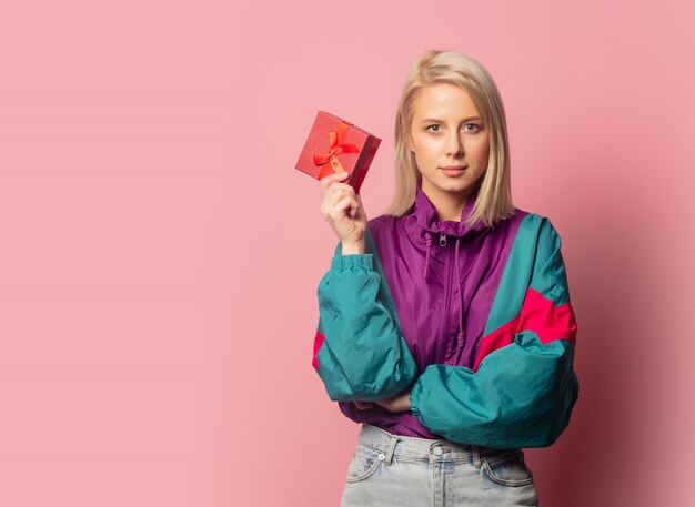 Hermosa mujer rubia en ropa de los años 90 con caja de regalo