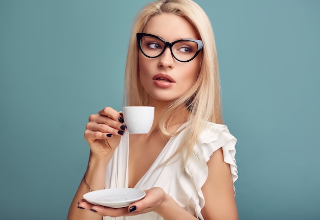 Hermosa mujer rubia sensual en vestido blanco con taza de café