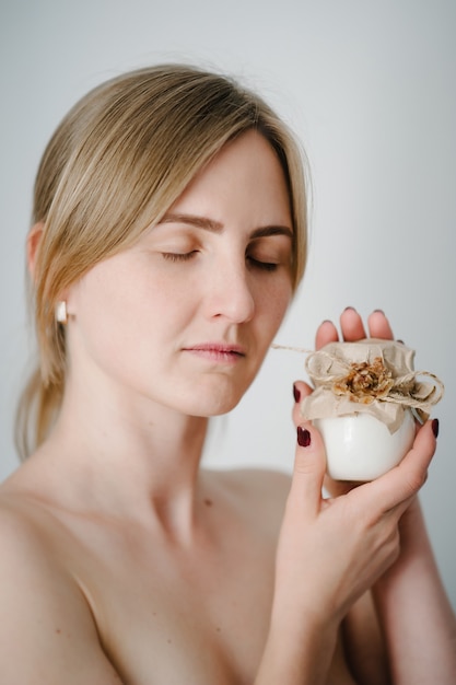 Hermosa mujer rubia sosteniendo una botella de crema hidratante