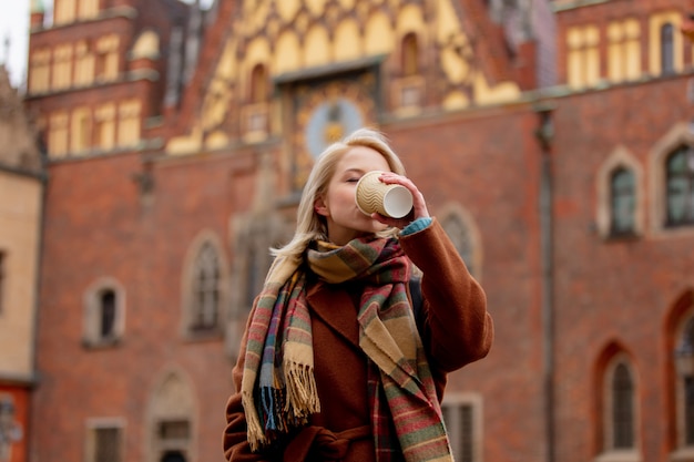 Hermosa mujer rubia tomar un café en el casco antiguo