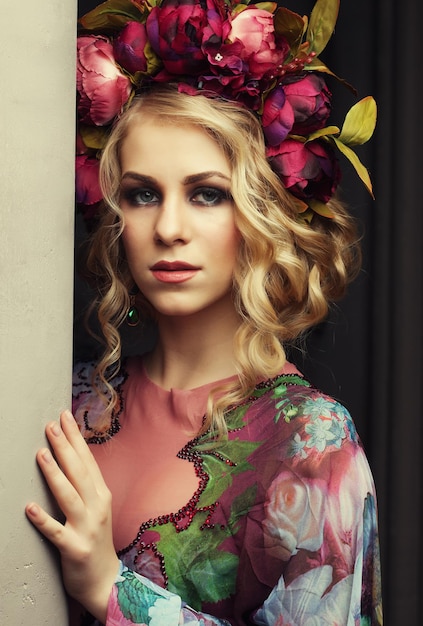 Hermosa mujer rubia con un vestido de colores florales con corona de flores