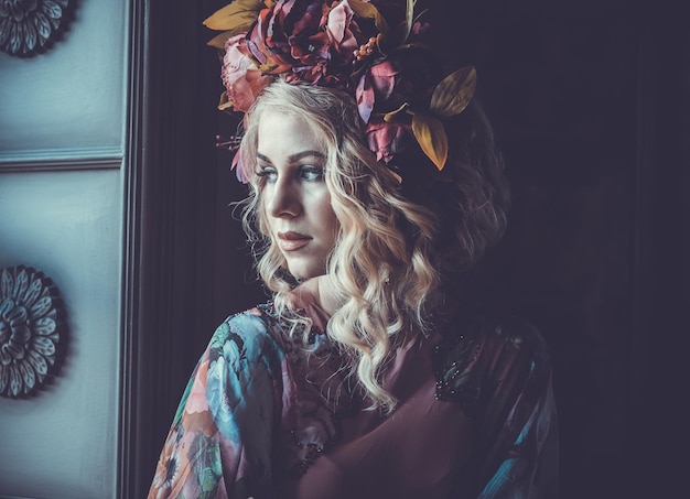 Hermosa mujer rubia con un vestido de colores florales se encuentra en el palacio