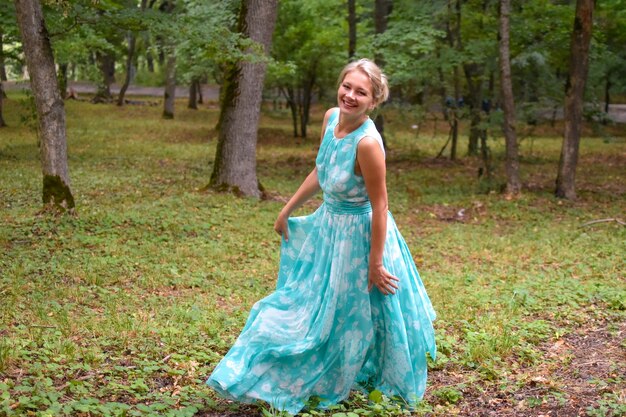 Hermosa mujer rubia en vestido largo está bailando al aire libre en escalones de piedra