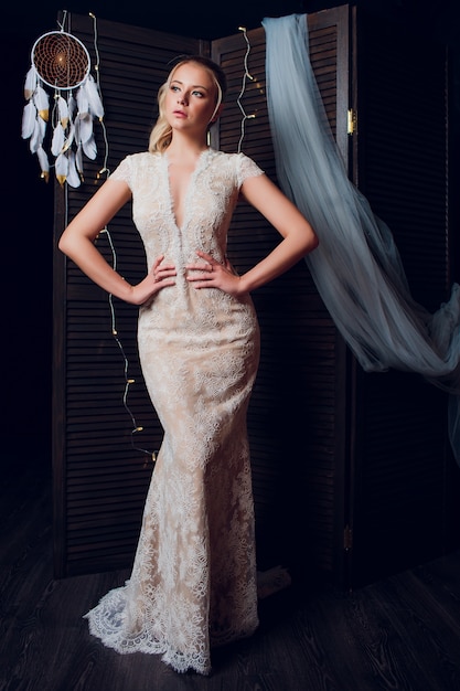 Hermosa mujer rubia con vestido romántico que fluye caminando en tiro de campo rural