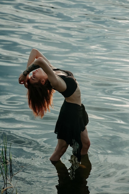 Hermosa mujer salvaje bailando una danza libre chamánica ritual entre las olas al atardecer.