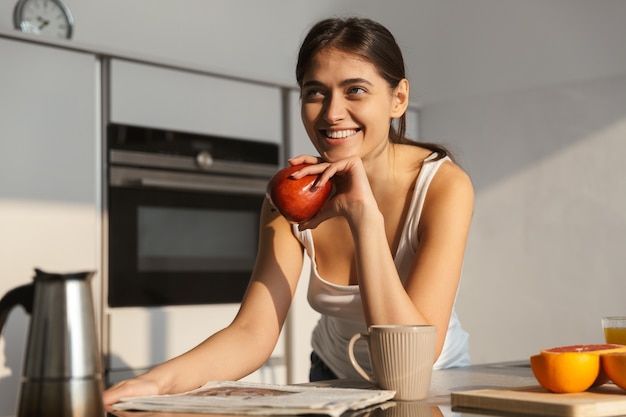 Hermosa mujer sana en la cocina con rutina matutina de manzana.