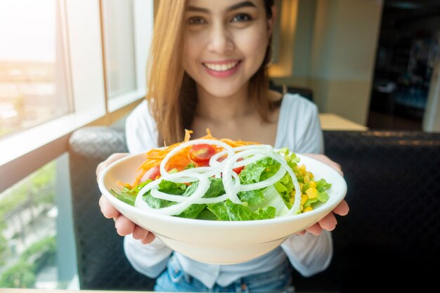 Hermosa mujer sana tiene ensalada de verduras