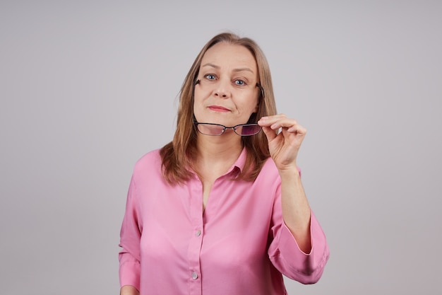 Hermosa mujer senior en blusa rosa se quita las gafas