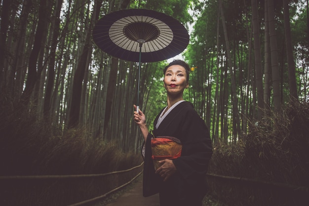 Hermosa mujer senior japonesa caminando en el bosque de bambú