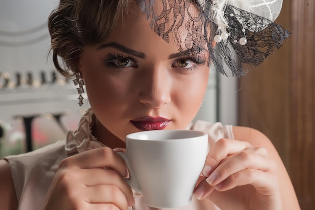 Hermosa mujer sensual con el pelo largo y oscuro en un lujoso vestido de lentejuelas posando en un café de verano