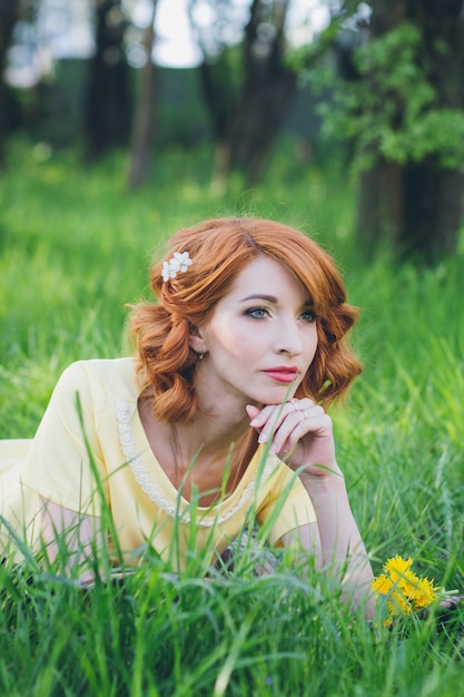 Hermosa mujer sensual con el pelo rojo en el jardín de primavera