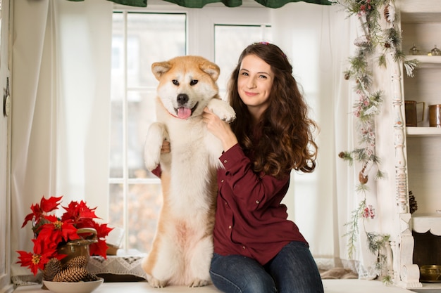 Hermosa mujer sentada aparador de árbol retro. abrazos, caricias con su perro akita inu.