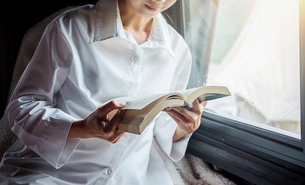 Hermosa mujer sentada en la cama y leyendo un libro