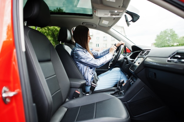 Hermosa mujer sentada dentro del coche con puerta abierta