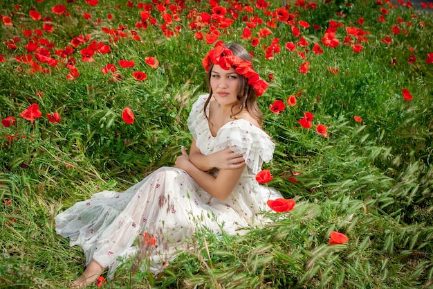 Hermosa mujer sentada en la flor de amapola